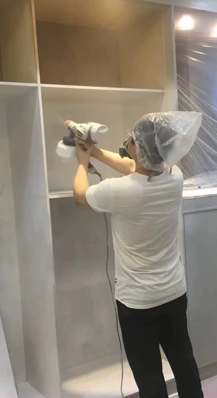 using protective gears while using a paint sprayer painting a cabinet